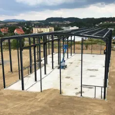 Stalowa konstrukcja pod płyty warstwowe na placu budowy. W tle widać miasteczko i wzgórza.