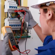 Elektryk sprawdza instalację, by ustalić, ile kosztuje przegląd instalacji elektrycznej. Miernik pokazuje 235V.