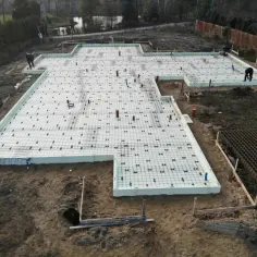 Budowa wylewki pod garaż. Na placu budowy widać fundamenty z izolacją i zbrojeniem, gotowe do zalania betonem.