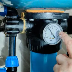 Palec wskazujący na manometr hydroforu, kontrolując ciśnienie przed odpowietrzeniem.