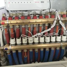 Rotametry na zasilaniu pokazują przepływ w instalacji ogrzewania podłogowego. Białe głowice termoelektryczne sterują powrotem.