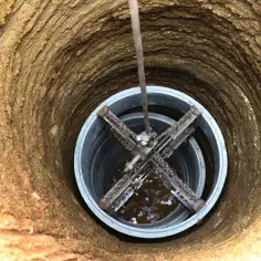 Narzędzie do kopania studni wciągane na linie. Widok z góry na wnętrze wykopu i mechanizm.