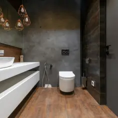 Nowoczesna łazienka z betonem architektonicznym na ścianach, który imituje mikrocement na płytki. Drewnopodobne płytki na podłodze.