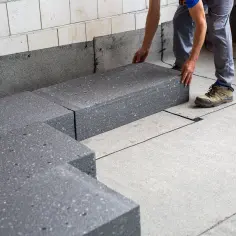 Układanie płyt izolacyjnych, które posłużą jako folia pod wylewkę na gruncie. Budowa fundamentów.