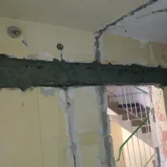 Świeżo położony podciąg z zaprawy nad otworem w ścianie. W tle widać schody.