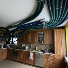 W kuchni starego domu instalacja rekuperacji tworzy gęstą sieć zielonych i niebieskich rur na suficie.