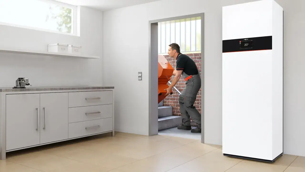 Jaki piec gazowy do domu 100m2? Instalator wnosi nowy, biały piec gazowy.