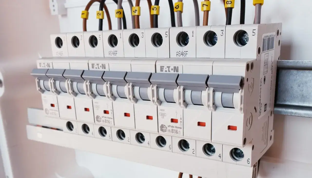 Instalacja elektryczna z wyłącznikami nadprądowymi. Widać oznaczenia typu HN-B16/3, co sugeruje, jaki bezpiecznik do gniazdek będzie odpowiedni.