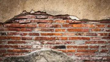 Odkryta ceglana ściana, odsłaniająca proces, jak wyrównać ściany w starym domu.